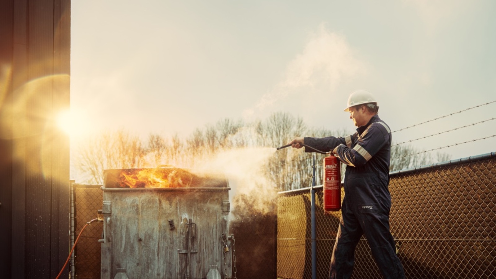 Man met brandblusser blust brand in een afval container.